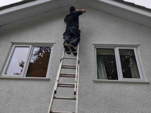 24-hour electrician from Electrust Electrical working on outdoor wiring at a residential property, standing on a ladder.