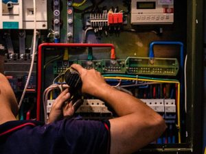 Electrician working on a complex electrical panel with multicolored wires, representing EV charger installation in Bolton by Electrust Electrical.